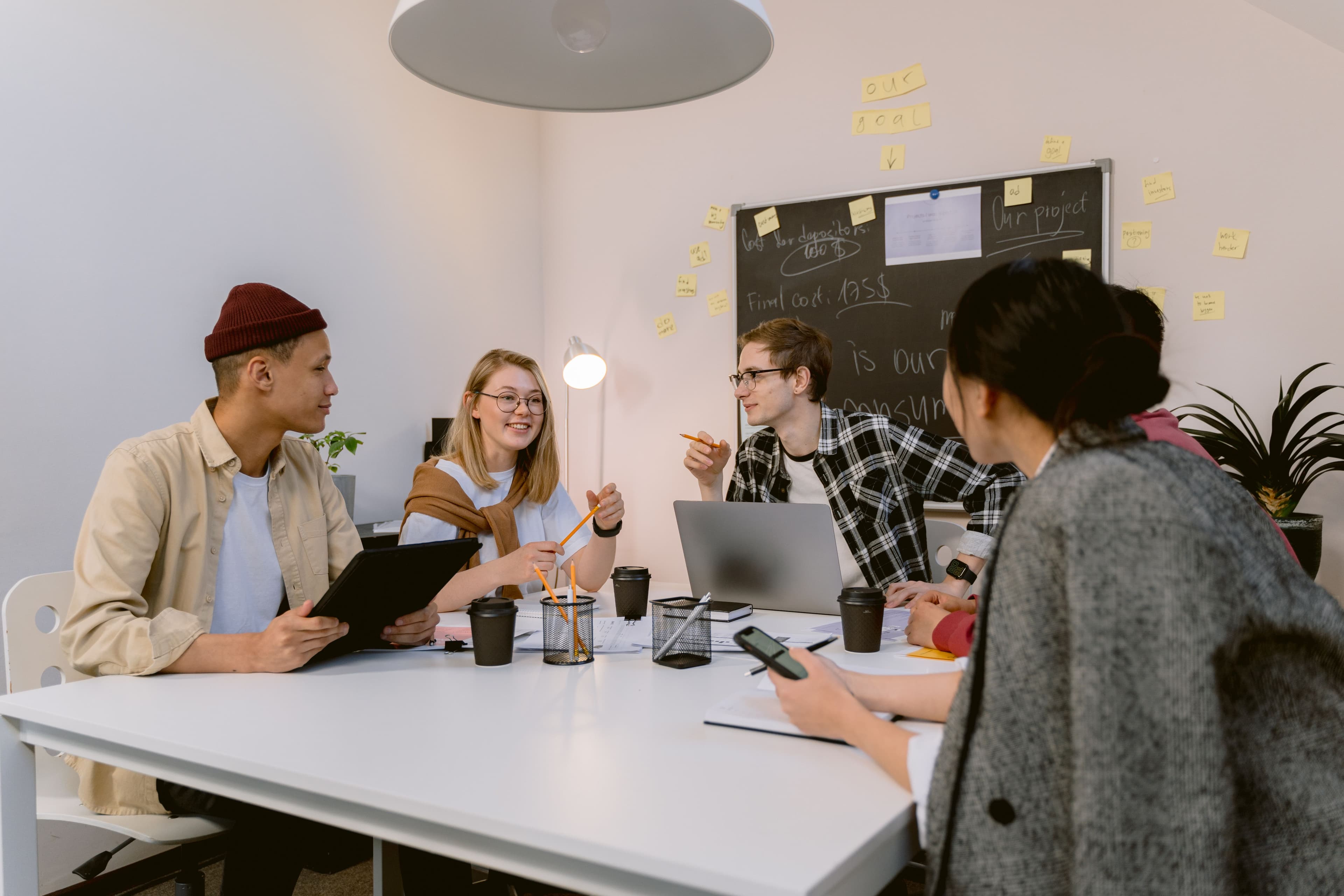 A group of young adults discussing ideas together around a laptop.